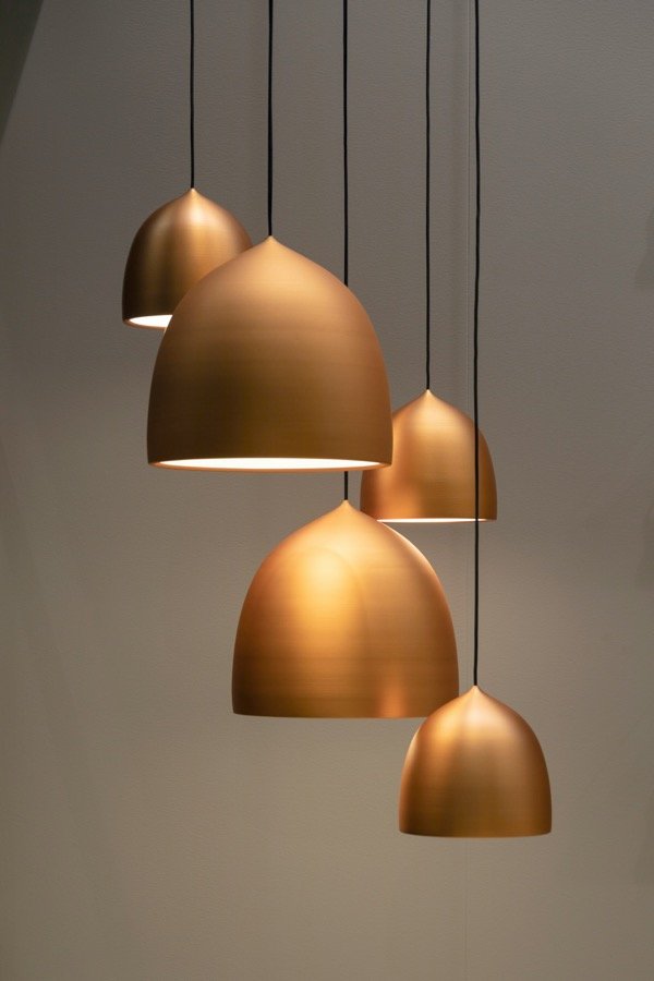 A cluster of brushed copper pendant lights hanging at varying heights